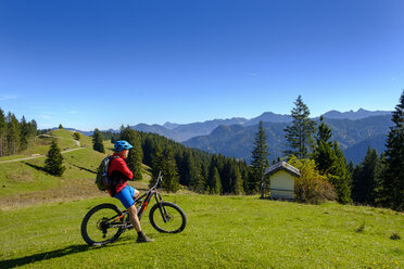 Germany, Mountainbiker looking to Hirschtalsattel, Aueralm with Tegernsee Mountains near Lenggries - LBF02366