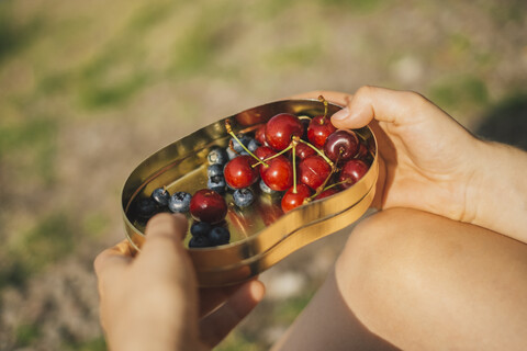 Frauenhand hält Dose mit Kirschen und Blaubeeren, Nahaufnahme, lizenzfreies Stockfoto