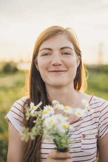 Porträt einer lächelnden jungen Frau mit einem Strauß gepflückter Wildblumen - JSCF00143