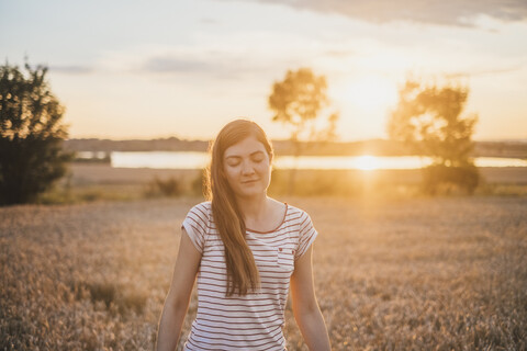 Porträt einer jungen Frau, die sich bei Sonnenuntergang in der Natur entspannt, lizenzfreies Stockfoto