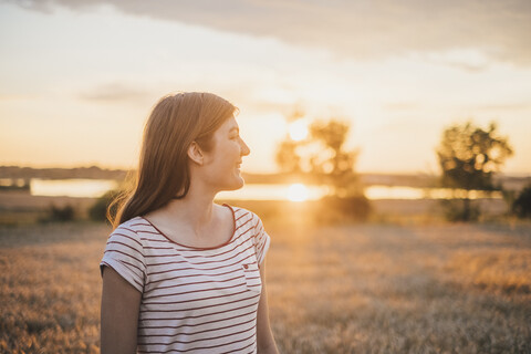 Smiling young woman enjoying sunset in nature stock photo