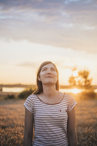 Porträt einer jungen Frau, die sich bei Sonnenuntergang in der Natur entspannt, lizenzfreies Stockfoto