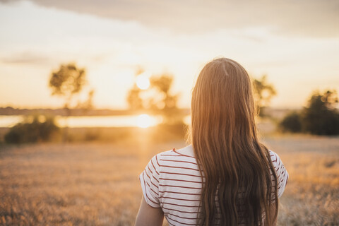 Back view of young woman watching sunset stock photo