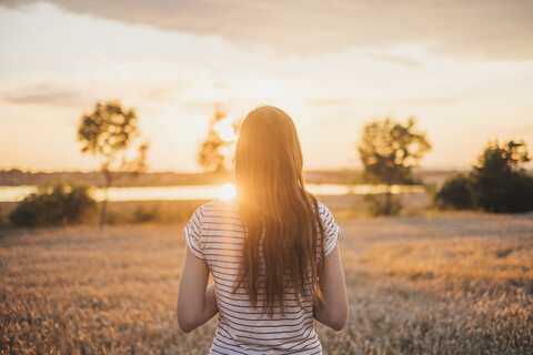 Back view of young woman watching sunset stock photo