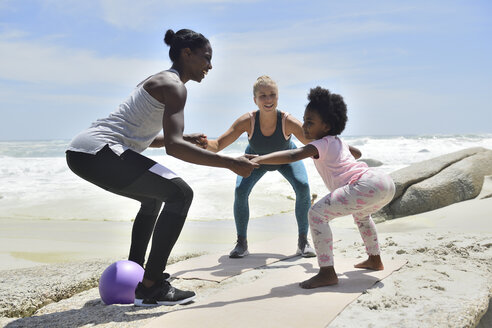 Mutter mit Tochter und Freund bei einer Fitnessübung am Strand - ECPF00383