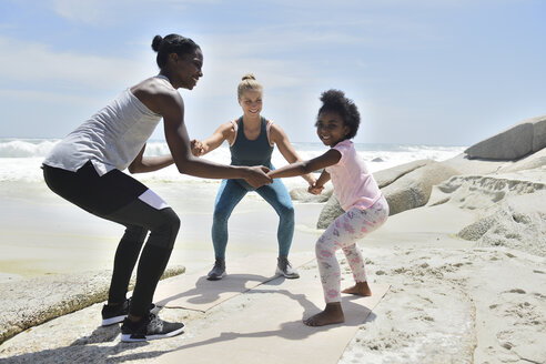 Mutter mit Tochter und Freund bei einer Fitnessübung am Strand - ECPF00385