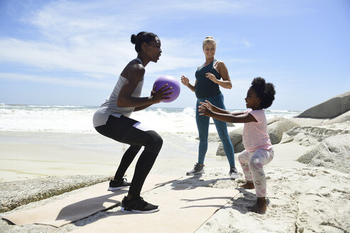 Mutter mit Tochter und Freund beim Training mit einem Ball am Strand - ECPF00397