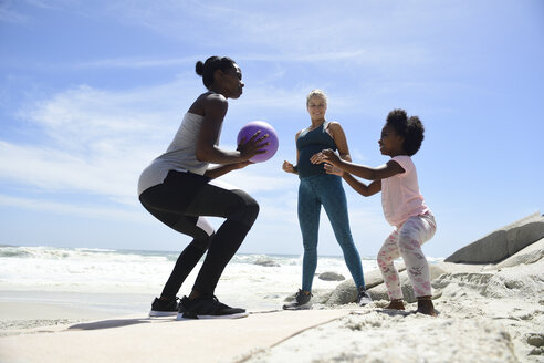 Mutter mit Tochter und Freund beim Training mit einem Ball am Strand - ECPF00398
