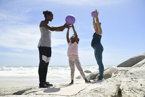 Mutter mit Tochter und Freund beim Training mit einem Ball am Strand - ECPF00401