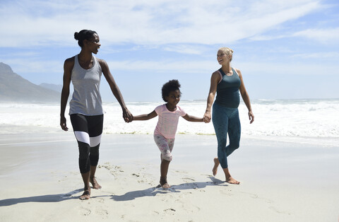 Glückliche Mutter mit Tochter und Freund beim Spaziergang am Strand, lizenzfreies Stockfoto