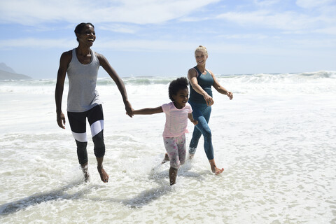 Mutter mit Tochter und Freund haben Spaß in der Brandung am Strand, lizenzfreies Stockfoto