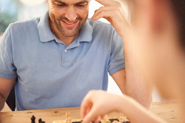 Junge und Vater spielen eine Partie Schach am Wohnzimmertisch, über die Schulter, Nahaufnahme - CUF48519