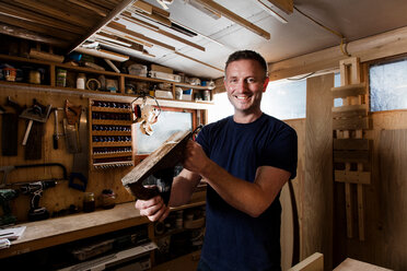 Craftsman holding wood plane in workshop - CUF48593