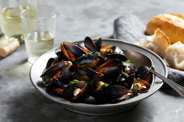Bowl of garlic mussels with glass of white wine - CUF48631