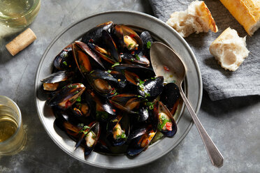 Bowl of garlic mussels with glass of white wine, overhead view - CUF48632