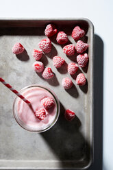 Raspberry yogurt smoothie with frozen raspberries on baking tray, overhead view - CUF48643