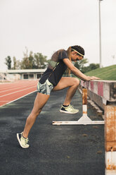 Female athlete doing warm-up exercises on tartan track - ACPF00439