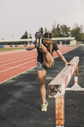 Female athlete doing warm-up exercises on tartan track - ACPF00440