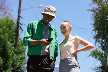 Junger Mann und Freundin schauen in einem Vorort auf ihr Smartphone, Los Angeles, Kalifornien, USA - CUF48684
