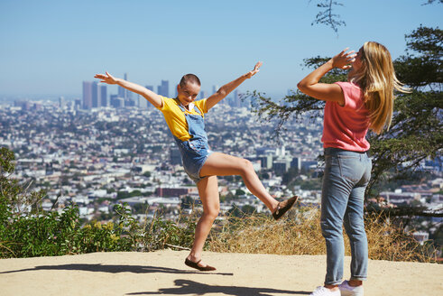Zwei junge Freundinnen amüsieren sich auf einem Hügel über der Stadt, Los Angeles, Kalifornien, USA - CUF48707