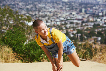 Teenager-Mädchen mit kurzgeschnittenen Haaren balanciert auf einem Bein auf einem Hügel in der Stadt, Los Angeles, Kalifornien, USA - CUF48708