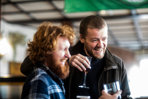 Zwei männliche Kunden lachen in einer traditionellen irischen Kneipe, lizenzfreies Stockfoto