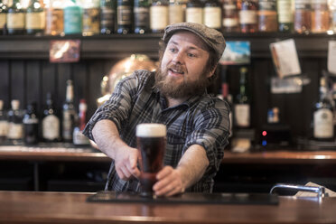 Barkeeper, der in einem traditionellen irischen Gasthaus Bier aus der Bar serviert - CUF48847