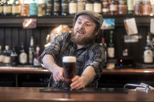 Barkeeper, der in einem traditionellen irischen Gasthaus Bier aus der Bar serviert - CUF48847