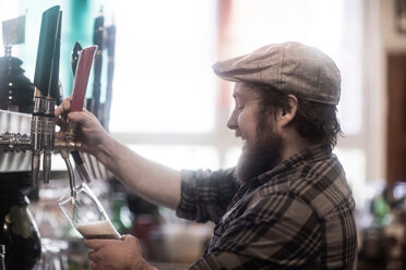 Barkeeper, der in einem traditionellen irischen Gasthaus Bier aus einer Pumpe ausschenkt - CUF48853