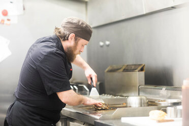 Fast-Food-Mitarbeiter brät Burger in Großküche - CUF48857