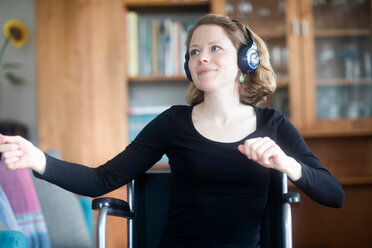 Frau im Rollstuhl tanzt zu Musik über Kopfhörer - CUF48950