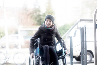 Woman in wheelchair moving up ramp - CUF48952