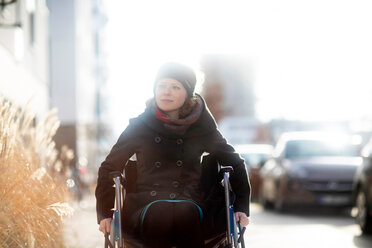 Woman in wheelchair in street - CUF48956