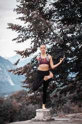 Frau übt Yoga, balanciert auf einem Bein auf einem Sockel, Berglandschaft, Domodossola, Piemonte, Italien - CUF49003