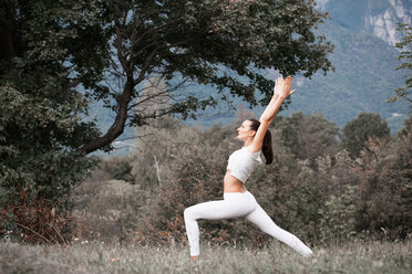 Frau übt Yoga, Kriegerpose in ländlicher Landschaft - CUF49006