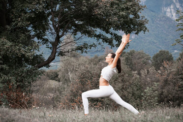 Woman practicing yoga, warrior pose in rural landscape - CUF49006