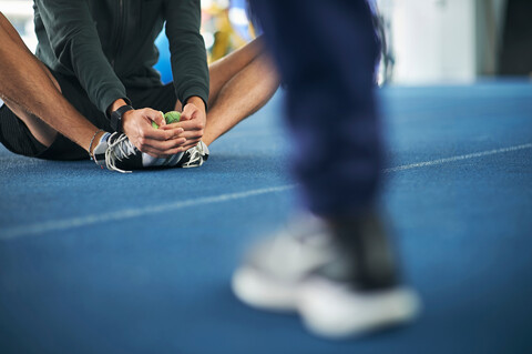 Läuferin beim Dehnen auf der Indoor-Laufbahn, lizenzfreies Stockfoto