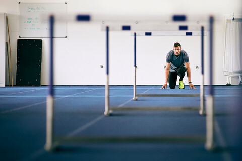 Ein Athlet bereitet sich auf die Hürden auf der Indoor-Laufbahn vor, lizenzfreies Stockfoto