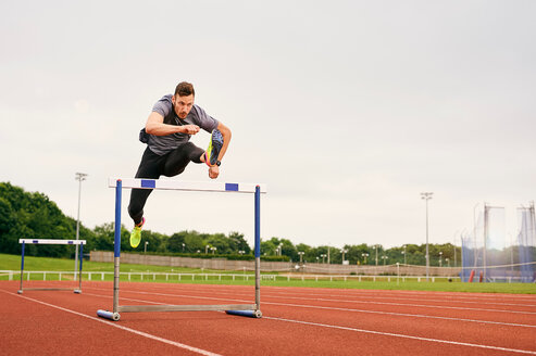 Athlet springt über Hürde auf Laufbahn - CUF49068
