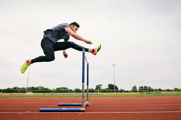 Athlet springt über Hürde auf Laufbahn - CUF49069