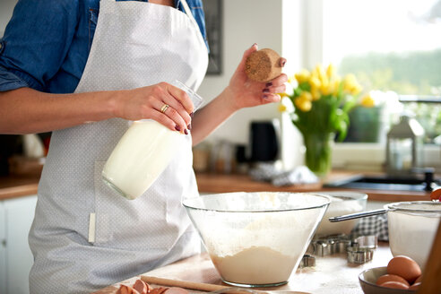 Frau gießt Milch in eine Rührschüssel in der Küche - CUF49115