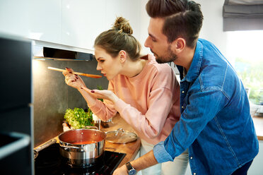 Couple tasting tomato soup in kitchen - CUF49125