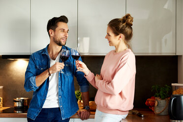 Couple talking and drinking red wine in kitchen - CUF49127