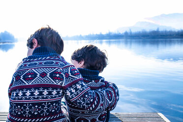Junge und kleiner Bruder in zusammenpassenden Pullovern sitzen auf dem Pier, Comer See, Lecco, Lombardei, Italien - CUF49219