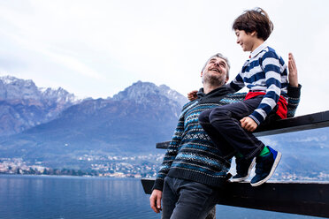 Junge und Vater sitzen auf dem Zaun eines Stegs, Comer See, Onno, Lombardei, Italien - CUF49253