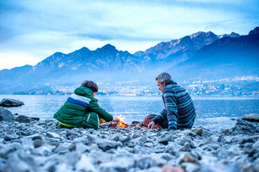 Vater und Sohn machen ein Lagerfeuer, Onno, Lombardei, Italien - CUF49259