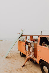 Young female surfer sitting on recreational vehicle on beach, portrait, Jalama, Ventura, California, USA - ISF20515