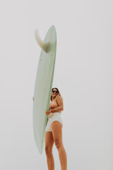 Young female surfer holding surfboard, low angle view, Jalama, Ventura, California, USA - ISF20518