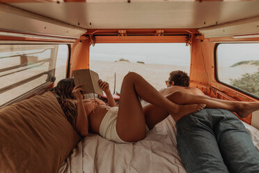 Young surfing couple lying in back of recreational vehicle at beach, Jalama, California, USA - ISF20524