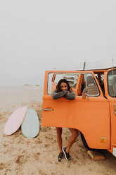 Young woman leaning on recreational vehicle window at beach, portrait, Jalama, California, USA - ISF20541